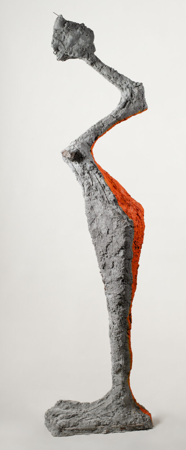 Rzeźba figury na jednej nodze, z pomarańczowym pasem na plecach